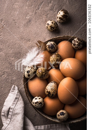 Chicken and quail eggs on brown background 106836382