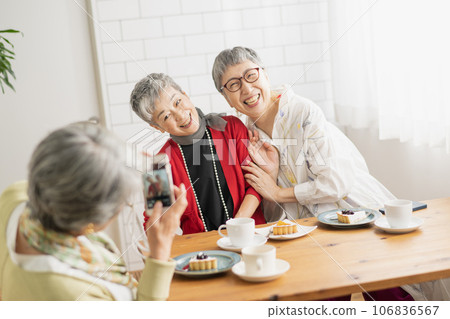 Senior women taking pictures at a cafe 106836567