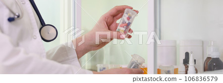Doctor puts box of pills on shelf in office. 106836579