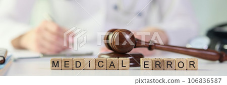 Words medical errors collected from wooden cubes with judge's gavel on table. 106836587