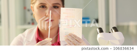 Scientist reviewing results of experiments and looking at paper with samples in research laboratory. Scientist reviewing results of experiments and looking at paper with samples in research laboratory. 106836634
