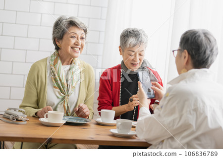 Senior friends having tea at a cafe Senior women looking at smartphones Senior friends having tea at a cafe Senior women looking at smartphones 106836789