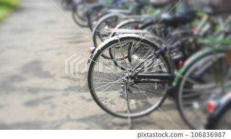 Many bicycles lined up at a bicycle storage area, blurred 106836987