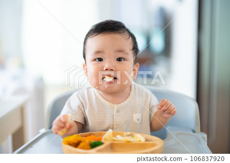 A 9-month-old baby who is in a good mood after grabbing and eating in the late stage of baby food A 9-month-old baby who is in a good mood after grabbing and eating in the late stage of baby food 106837920