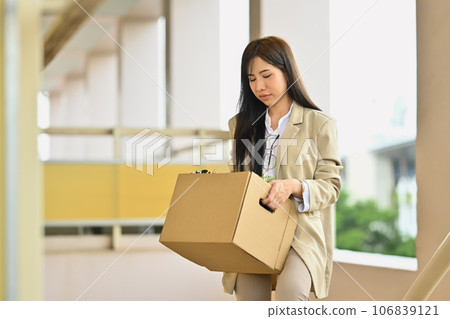 Upset female office worker leaving office with cardboard box full of belongings. Job loss, unemployed concept 106839121
