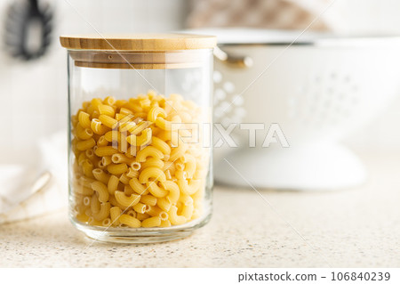 Raw macaroni pasta in glass bottle. Uncooked rigatoni in glass jar. 106840239