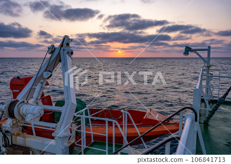 Tourists watching the sunset from the deck of a ship and clicking the camera shutter 106841713