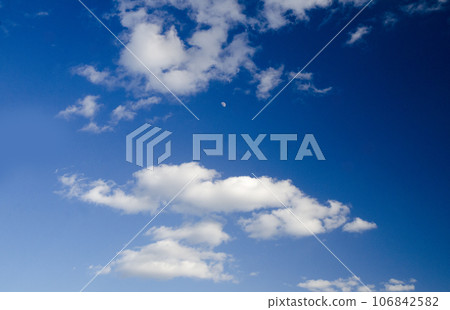 White clouds and the moon in the deep blue sky White clouds and the moon in the deep blue sky 106842582