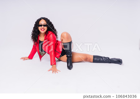 African American curvy female in black bodysuit and jacket on red and white background in studio 106843036