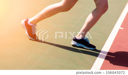 Legs of young girl in a closed tennis court with racket, sport shoes Legs of young girl in a closed tennis court with racket, sport shoes 106843072
