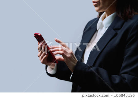 Closeup of business woman's hands using smartphone, on gray background 106843156
