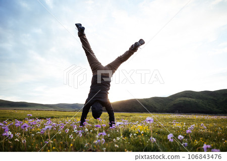 Woman hiker doing a handstand on high altitude mountain meadow 106843476