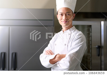 Image of a man in a chef's hat looking away while folding his arms. Image of a man in a chef's hat looking away while folding his arms. 106843659