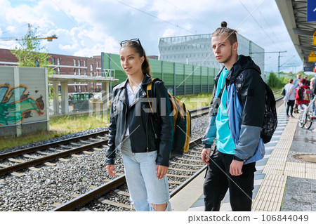 Students teenage guy and girl with backpacks waiting for commuter train on railway platform 106844049