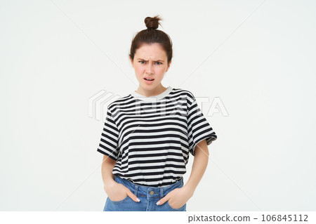 Image of bothered, disappointed young woman, frowning, complaining, looking angry and upset, standing over white background, arguing Image of bothered, disappointed young woman, frowning, complaining, looking angry and upset, standing over white background, arguing 106845112