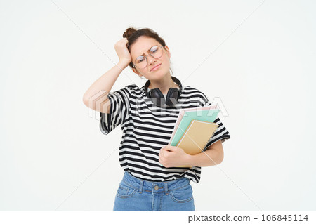 Image of upset young woman, student in glasses complains at difficult task at university, holding notebooks, forgot to do something, white background Image of upset young woman, student in glasses complains at difficult task at university, holding notebooks, forgot to do something, white background 106845114
