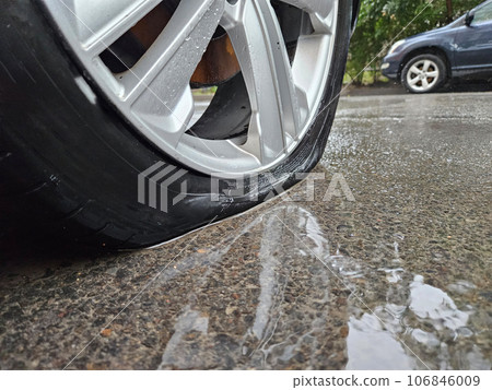 On a wet asphalt road, one of the tires is completely flat  106846009