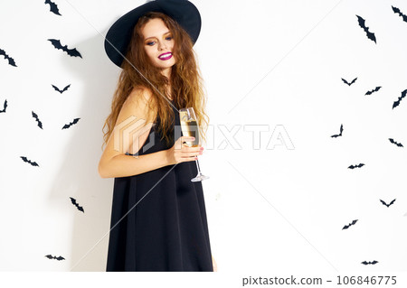 happy young woman in black witch halloween costume on party over white background with bats. 106846775