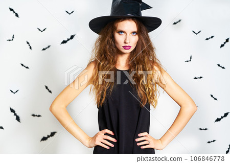 happy young woman in black witch halloween costume on party over white background with bats. happy young woman in black witch halloween costume on party over white background with bats. 106846778