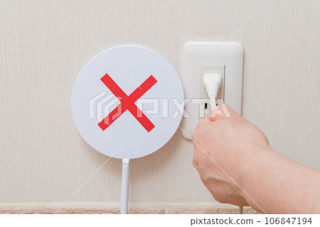 [Housewife holding the cord and unplugging the outlet] 106847194