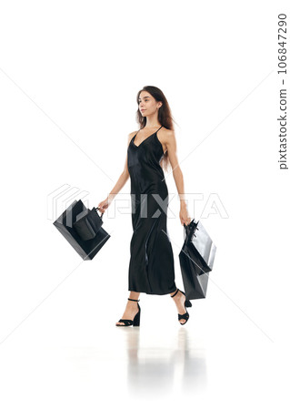 Cyber monday concept. Full lenght portrait of women wearing black long dreass holding bags in hands going shopping mall isolated on white background 106847290