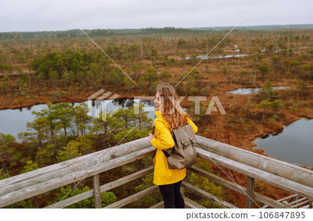 Young woman looks at amazing nature on observation deck. Tourist enjoys a view of magical swamps. 106847895