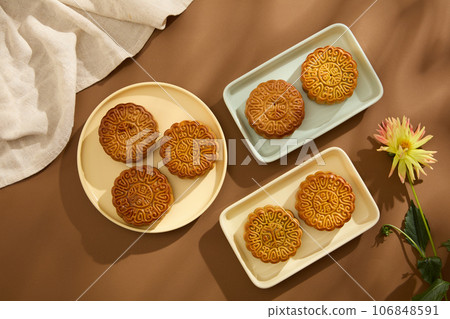 Delicious mooncakes with classic pattern are displayed on ceramic dishes in rectangle and round shaped. Brown background. Background food and drink tea and Mooncakes Delicious mooncakes with classic pattern are displayed on ceramic dishes in rectangle and round shaped. Brown background. Background food and drink tea and Mooncakes 106848591