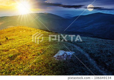 narrow path through grassy meadow among white stones on top of the hill in high mountain with sun and moon at twilight. day and night time change concept. mysterious nature scenery in morning light 106849134