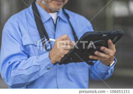 Hand of a man in work clothes typing on a tablet with a pen 106851151