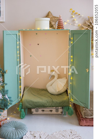 The interior of a children's room decorated for the Christmas holidays. A children's wardrobe with soft pillows and toys. 106852055