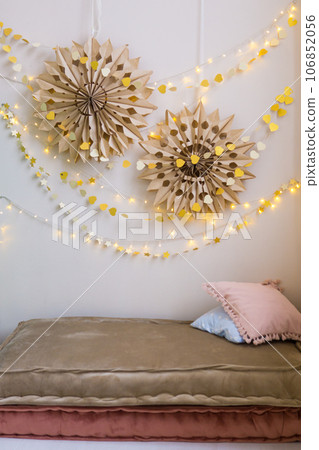 The interior of a children's room decorated for the Christmas holidays. Soft mattresses with garlands in the form of stars. The interior of a children's room decorated for the Christmas holidays. Soft mattresses with garlands in the form of stars. 106852056