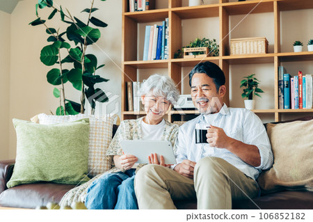 Senior couple looking at a tablet in the living room Senior couple looking at a tablet in the living room 106852182