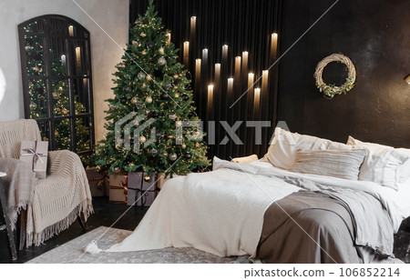 Bedroom interior decorated for Christmas holidays. Home interior with a Christmas tree on a dark wall background. 106852214