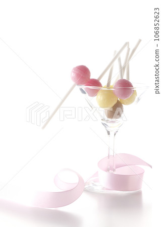 Cocktail glass, candy and ribbon photographed on white background Cocktail glass, candy and ribbon photographed on white background 106852623