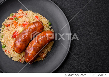 Delicious chicken or pork sausages baked on the grill with porridge and vegetables Delicious chicken or pork sausages baked on the grill with porridge and vegetables 106855034