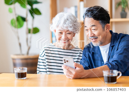 A senior couple looking at a smartphone together. 106857403