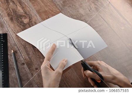 hands of an elderly woman fold origami paper. Creating an origami paper crane 106857585