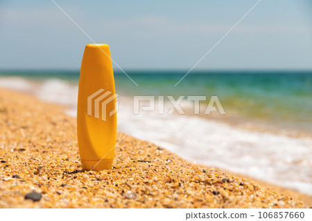 Empty textured sandy beach by the summer sea with a bottle of sun cream. empty cosmetic skincare cream or sunscreen on sandy beach with sea background, leisure and travel accessory Empty textured sandy beach by the summer sea with a bottle of sun cream. empty cosmetic skincare cream or sunscreen on sandy beach with sea background, leisure and travel accessory 106857660