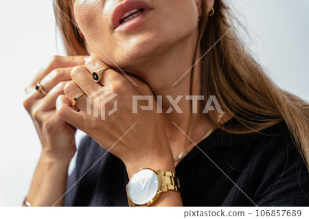 Attractive mature woman in black wear model showing golden bracelets, rings, chains on white background. Attractive mature woman in black wear model showing golden bracelets, rings, chains on white background. 106857689