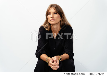Attractive mature woman in black wear model showing golden bracelets, rings, chains on white background. Attractive mature woman in black wear model showing golden bracelets, rings, chains on white background. 106857694
