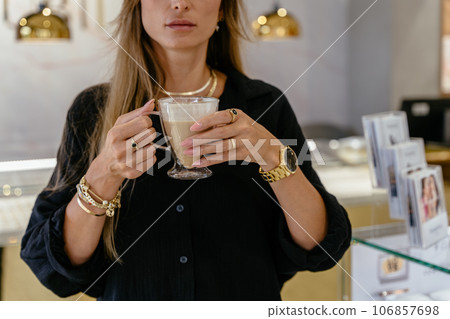 Unrecognizable woman in golden bracelets, rings, chains during work in a jewelry shop. Successful people in small business concept. 106857698