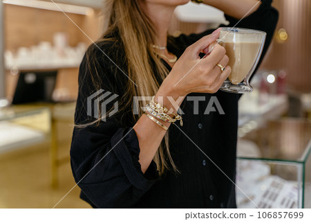 Unrecognizable woman in golden bracelets, rings, chains during work in a jewelry shop. Successful people in small business concept. 106857699