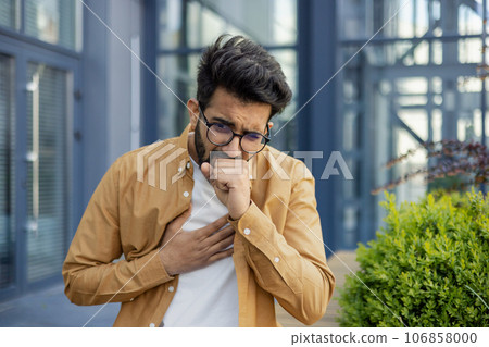 A sick man sits on the street, a businessman coughs outside an office building, a Latin American woman in casual clothes has a cold on a sunny day. A sick man sits on the street, a businessman coughs outside an office building, a Latin American woman in casual clothes has a cold on a sunny day. 106858000