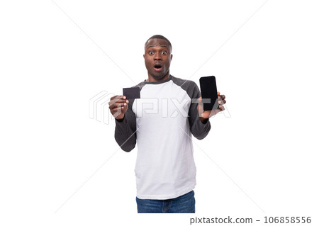 young american guy with short haircut holding credit card mockup and smartphone with mockup for 106858556