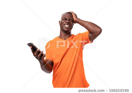 a young slender American man dressed in an orange cotton T-shirt with a mockup holds a smartphone in a young slender American man dressed in an orange cotton T-shirt with a mockup holds a smartphone in 106858590
