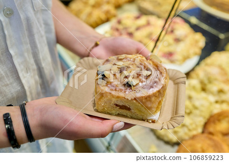 Bun with marzipan in hands, against the backdrop of display case in pastry bakery Bun with marzipan in hands, against the backdrop of display case in pastry bakery 106859223