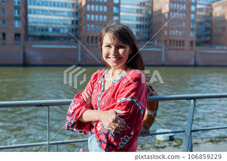 Mature smiling woman in embroidered shirt looking at camera, outdoor 106859229