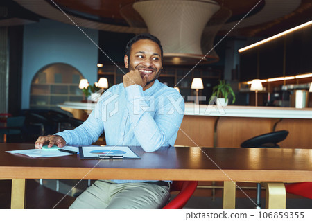 Happy male analyst working with documents while sitting on desk in coworking 106859355