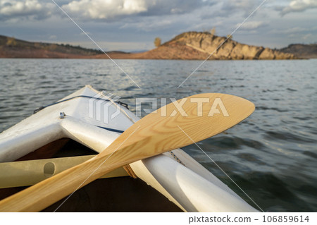bow of a decked expedition canoe with wooden paddle on a mountain lake, paddler view - Horsetooth Reservoir in northern Colorado 106859614