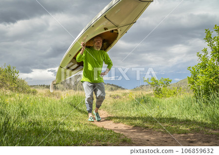 senior male is portaging a decked expedition canoe at foothills of northern Colorado in spring scenery senior male is portaging a decked expedition canoe at foothills of northern Colorado in spring scenery 106859632